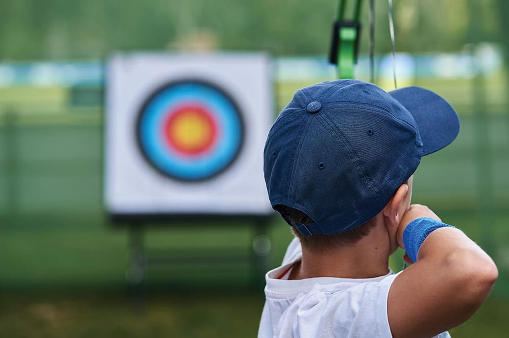 A kid shooting an arrow at an archery target.