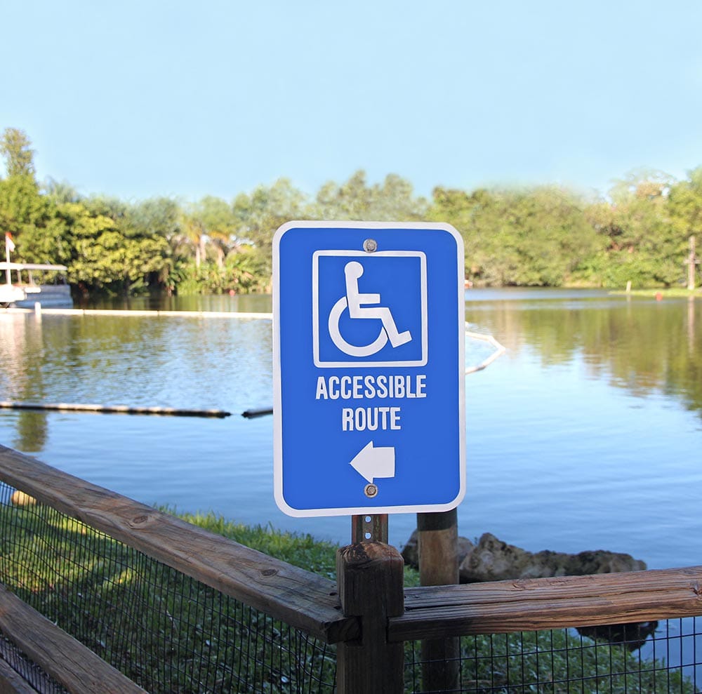 Sign in front of a pond that says "Accessible route" with an arrow pointing to the left.