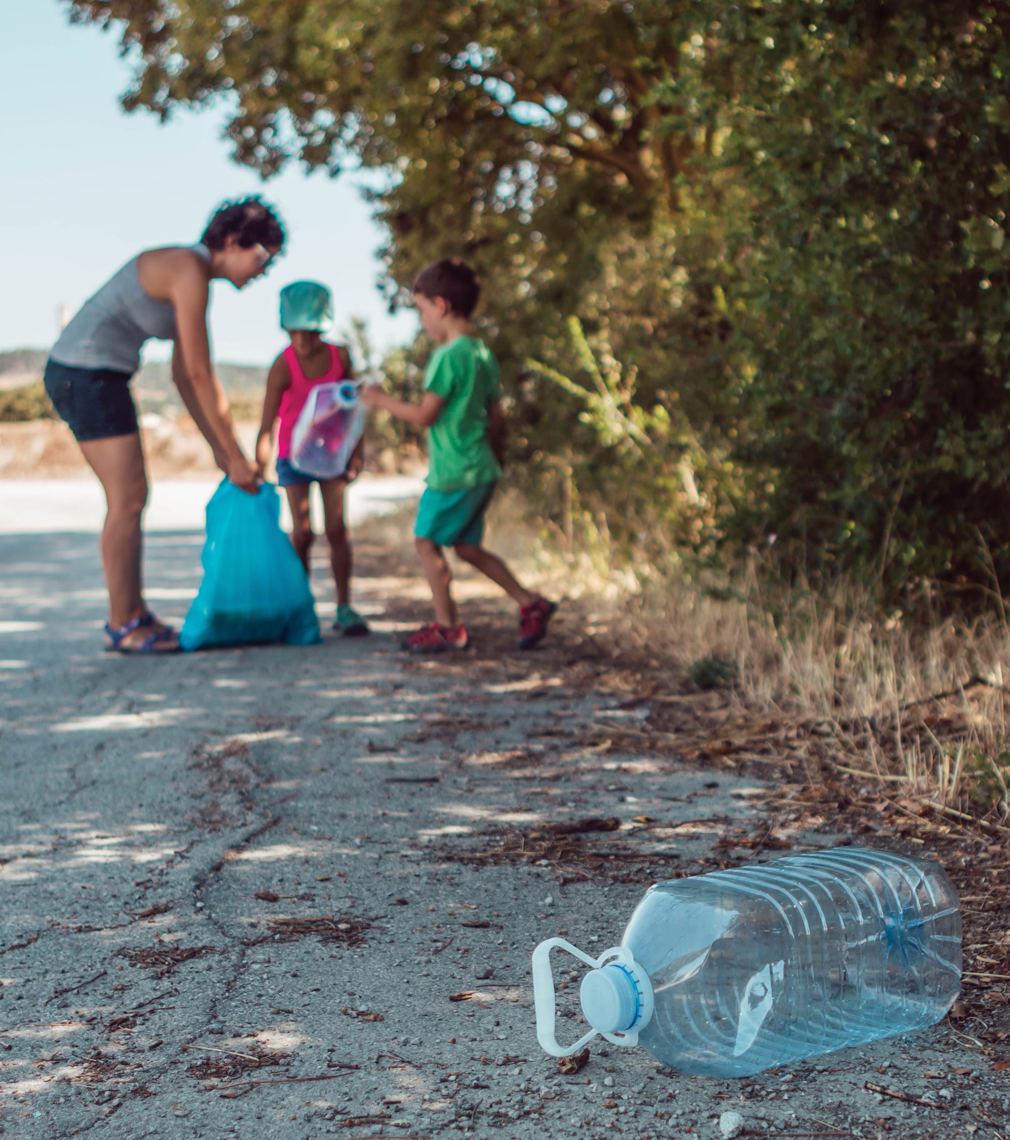 People picking up trash from dirt road