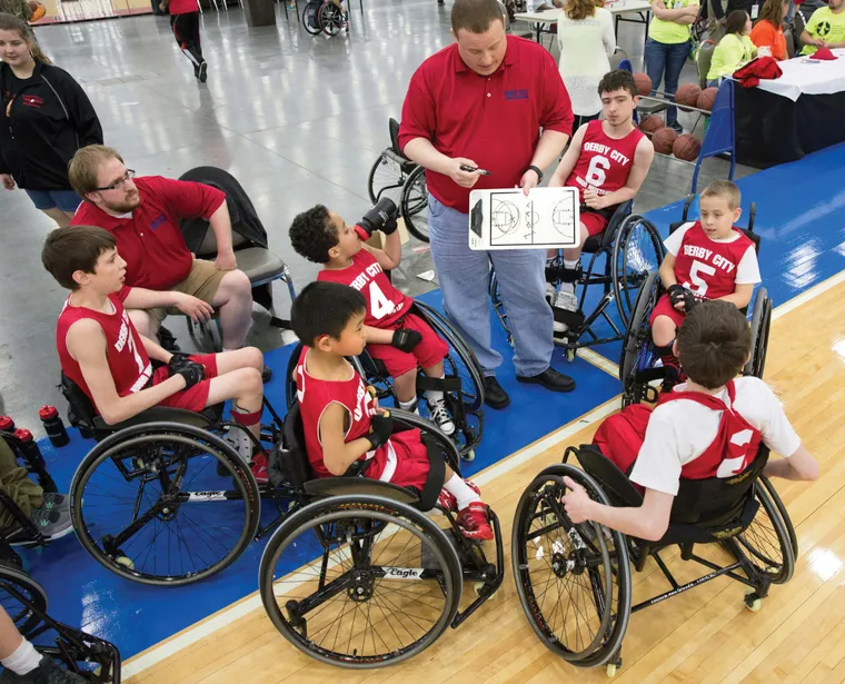 A couch showing an adaptive basketball team a play with his whiteboard