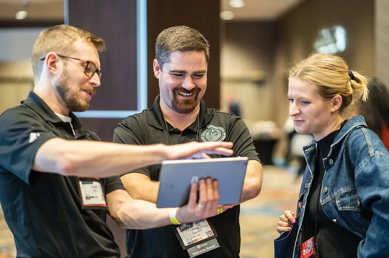 Group of people at a conference looking at an ipad.