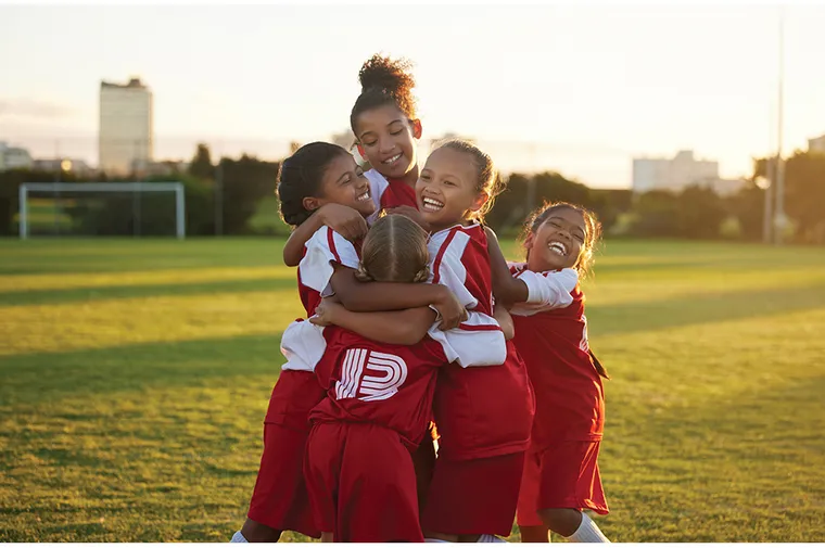 A group of black girls celebrating during a soccer game.